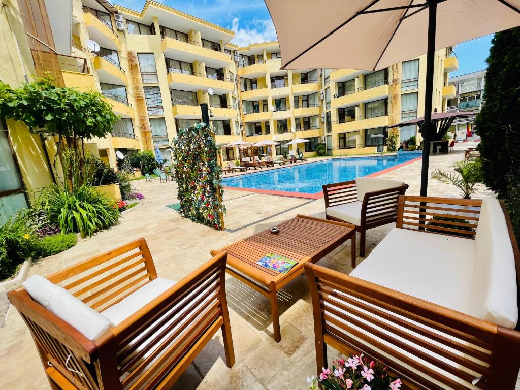 a swimming pool with two benches and an umbrella at Complex Sands Holiday Apartments in Sunny Beach
