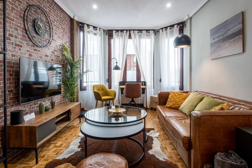 - un salon avec un canapé brun et un mur en briques dans l'établissement Palermo Beach by DLA, à Saint-Sébastien