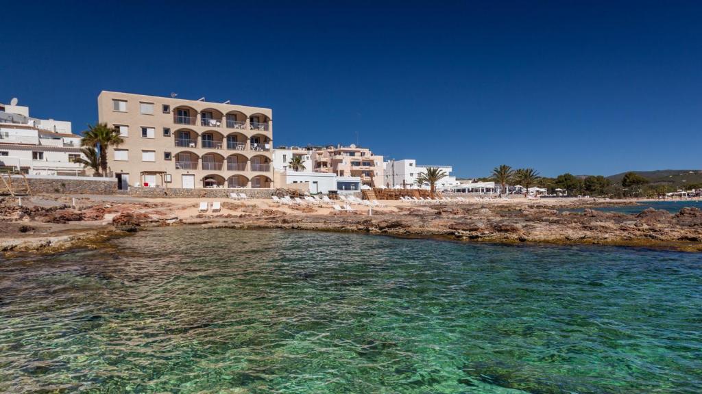 a body of water next to a beach with buildings at Zodiac Apartments in Es Cana