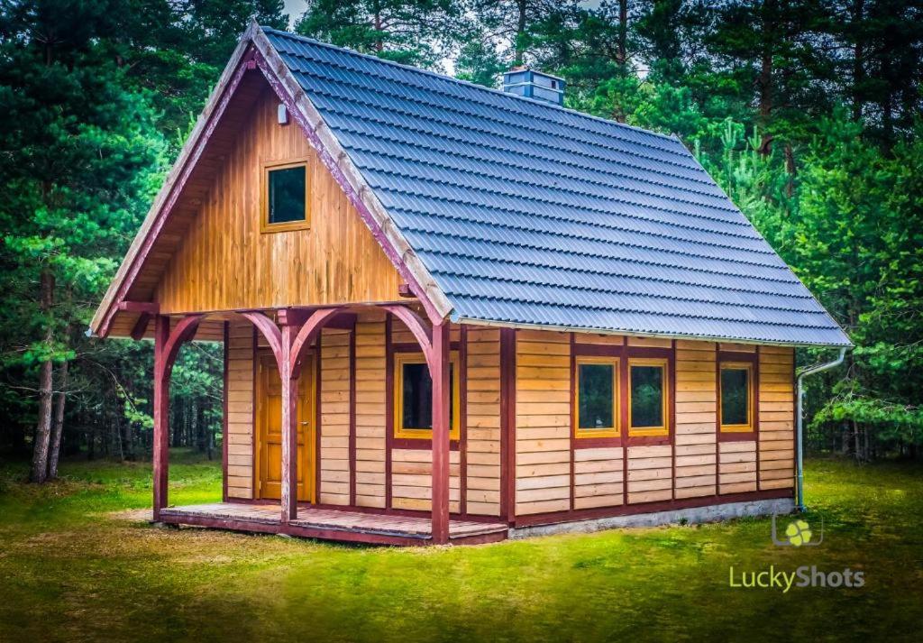 Cabaña de madera pequeña con techo azul en Chatka nad jeziorem, en Studzienice