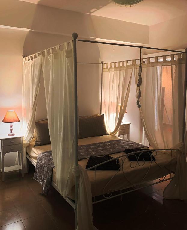 a bedroom with a four poster bed with curtains at Μaria's flats in Tolo