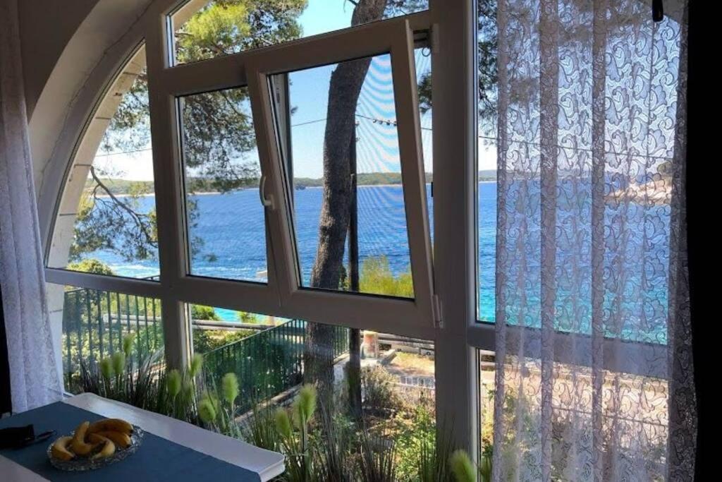 una ventana con vistas al océano desde una casa en Shabby chic beach cottage Hvar en Hvar