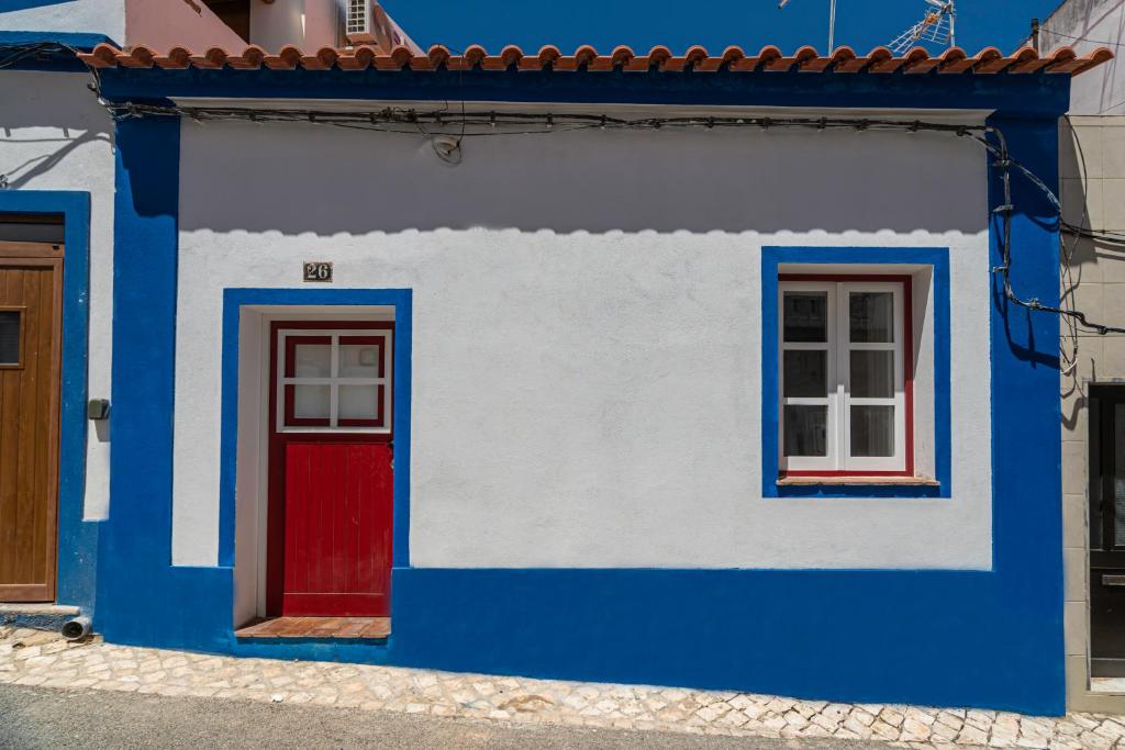 une maison bleue et blanche avec une porte rouge et des fenêtres dans l'établissement House in the Historic Center- Portimão, à Portimão