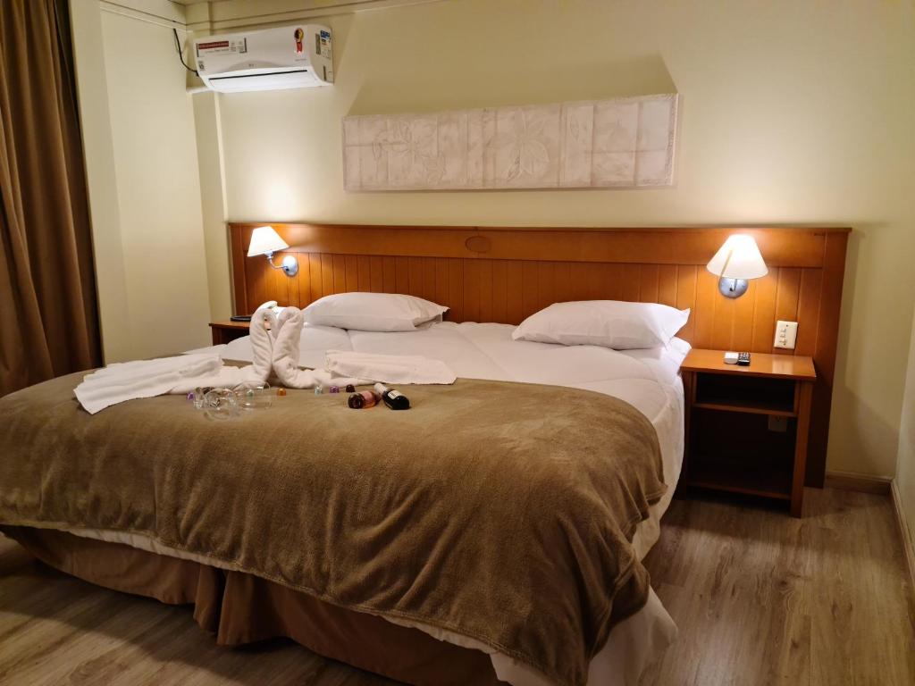 a hotel room with a large bed with towels on it at Alpenhaus Gramado Flat Temporada in Gramado