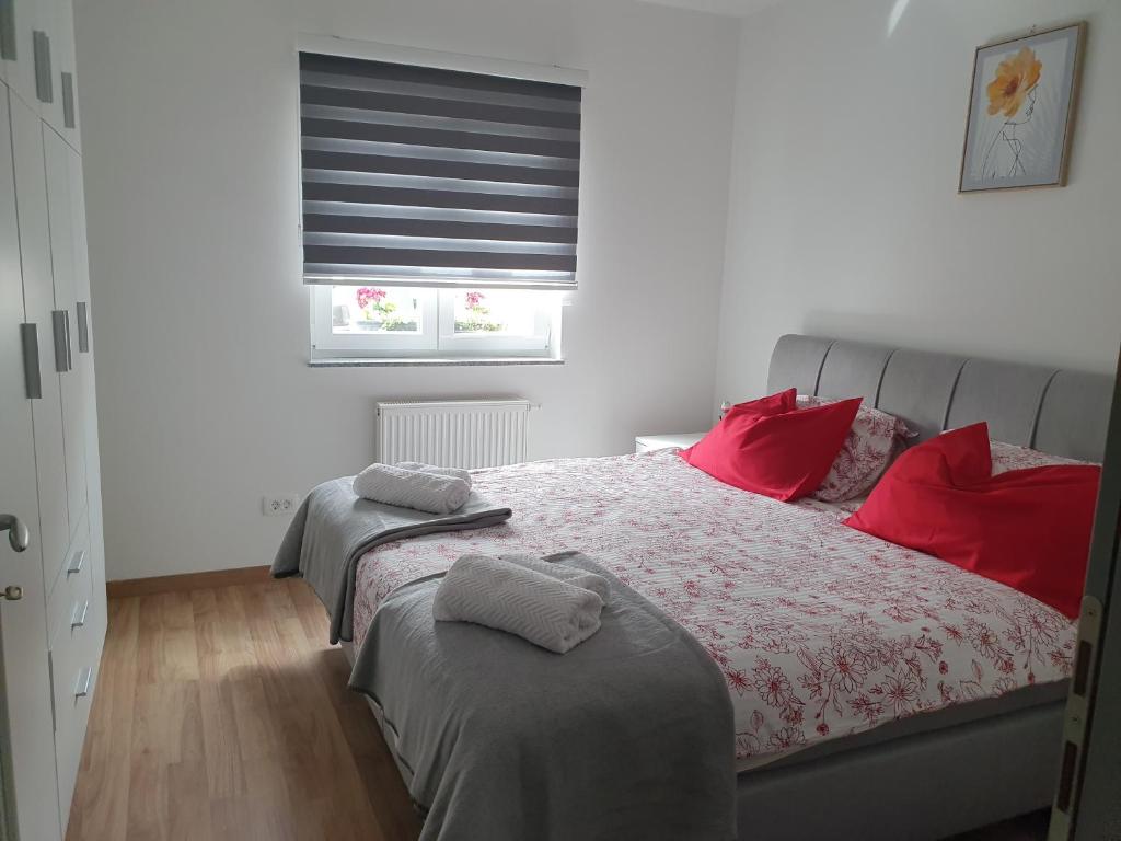 a bedroom with a bed with red pillows and a window at Apartmani Fenestra -Zagorka in Otočac
