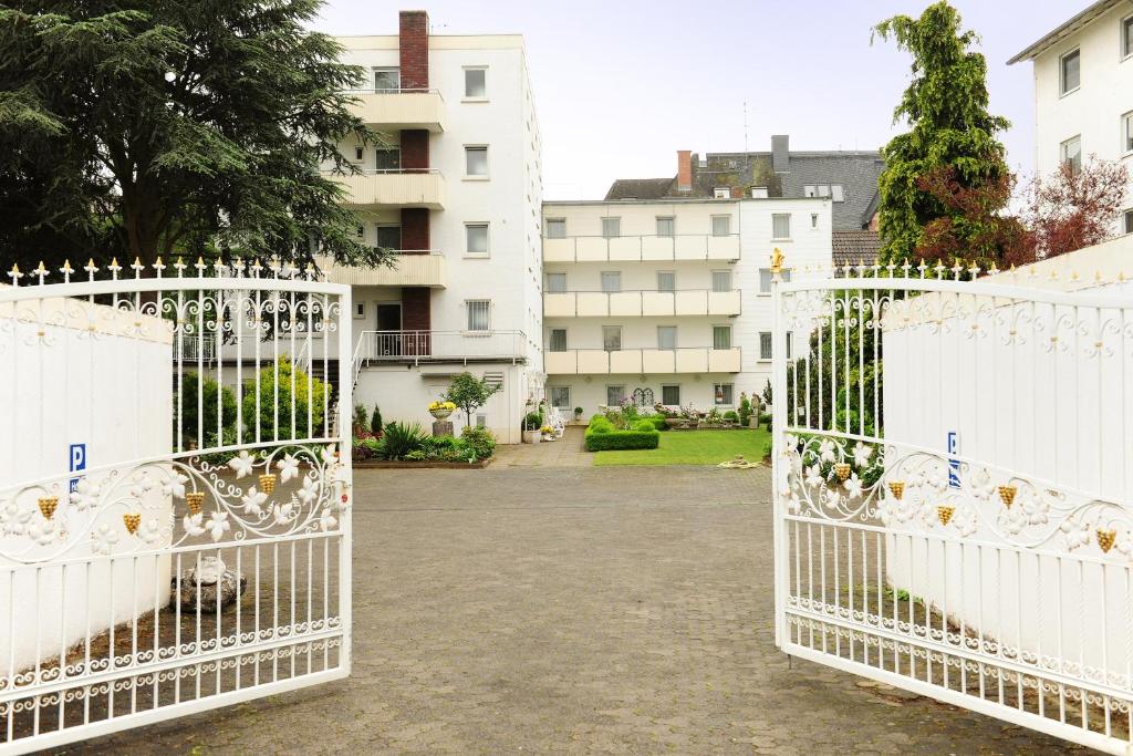 two white gates in a courtyard with buildings at Hotel Alte Post Garni in Ginsheim-Gustavsburg
