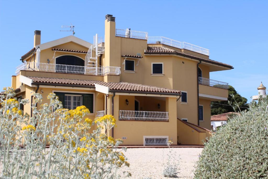 シラクーサにあるVilla Faro Massolivieriのバルコニー付きの大きな黄色の家