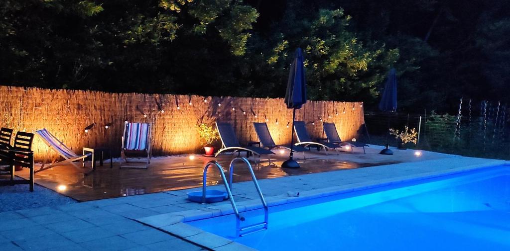 - une piscine avec chaises longues et parasols la nuit dans l'établissement Le Domaine de Villespy, à Villespy
