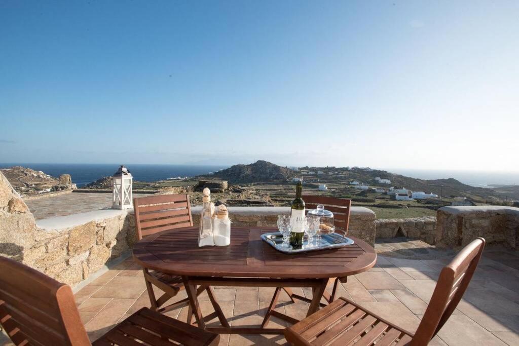 a wooden table and chairs on a patio with the ocean at Villa Jakie in Mýkonos City