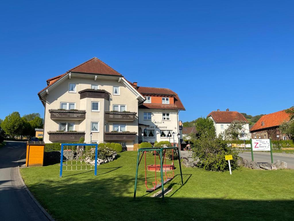 a yard with two playground equipment in front of a building at Gasthof Pension und Fewos Zur Zweere in Willingen