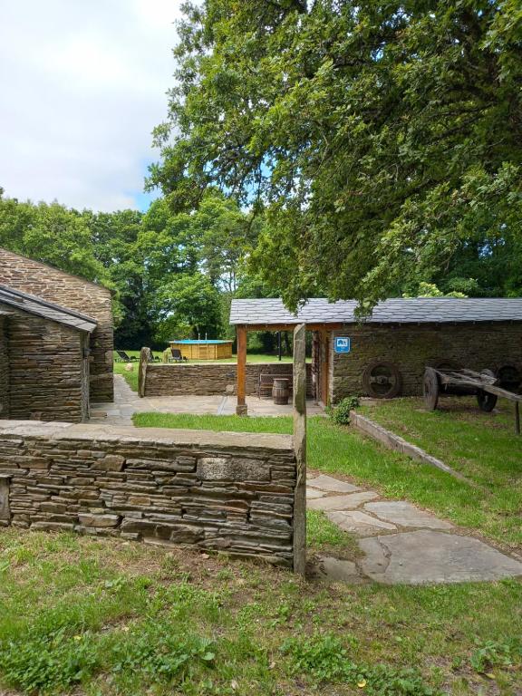 une clôture en pierre dans un parc avec un bâtiment dans l'établissement Albergue o Xistral, à Abadín