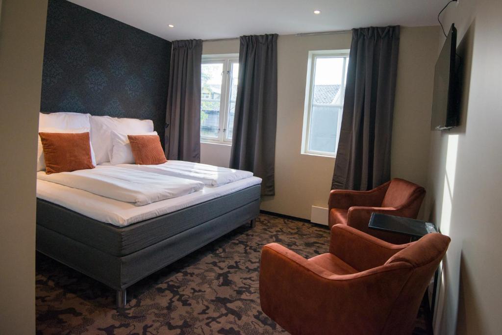 サンネシェーンにあるSandnessjøen Overnattingのベッド1台と椅子2脚が備わるホテルルームです。
