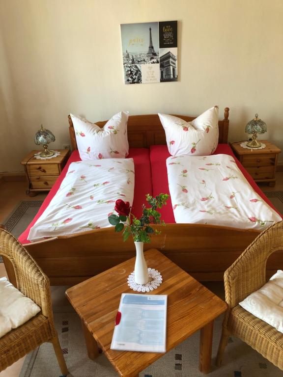 Zimmer mit einem Bett und einem Tisch mit einer Vase in der Unterkunft Pension „La Rose“ in Norden