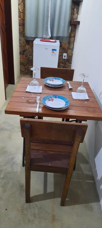 a wooden table with plates and wine glasses on it at Chalé bons ventos in Serra de São Bento