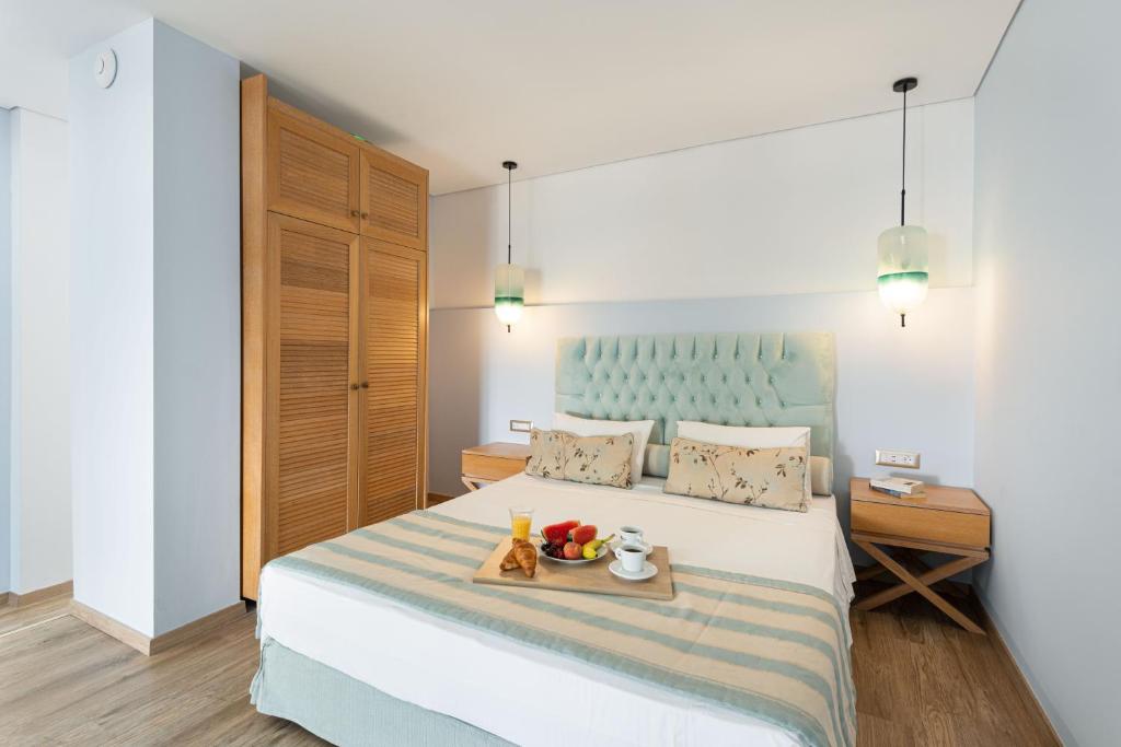 a bedroom with a bed with a tray of fruit on it at Regos Resort Hotel in Neos Marmaras