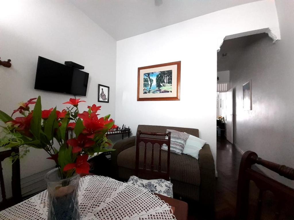 a living room with a couch and a table with red flowers at Apartamento Av Atlantica in Rio de Janeiro