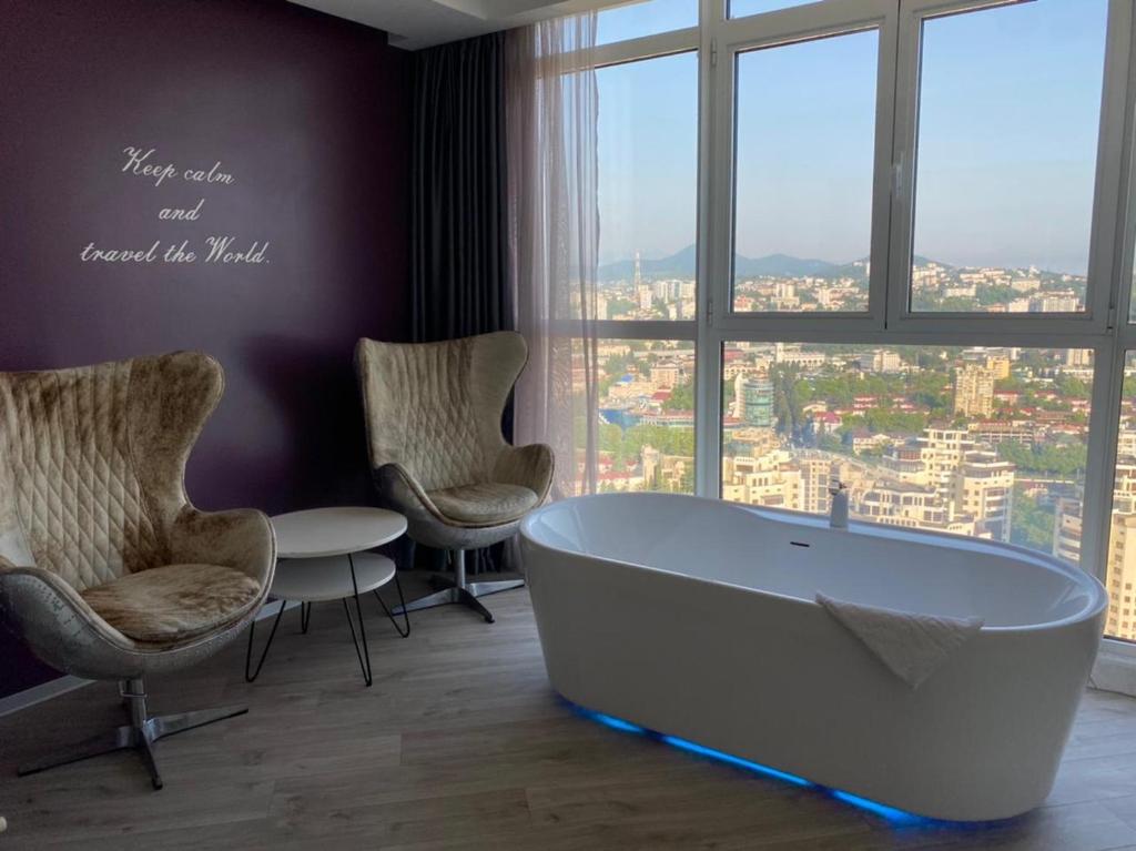 a bath tub in a room with chairs and a window at Residence Sky in Sochi