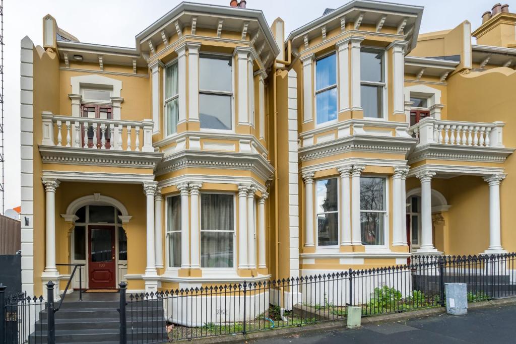 a yellow house with a fence in front of it at Inner City Executive Living on Stuart Street in Dunedin