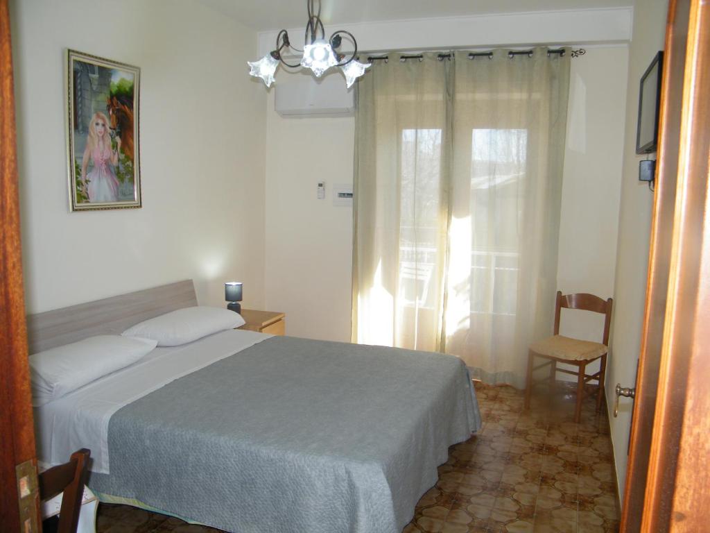 1 dormitorio con 1 cama, 1 silla y 1 ventana en Casa Buenos Aires, en Massa Lubrense