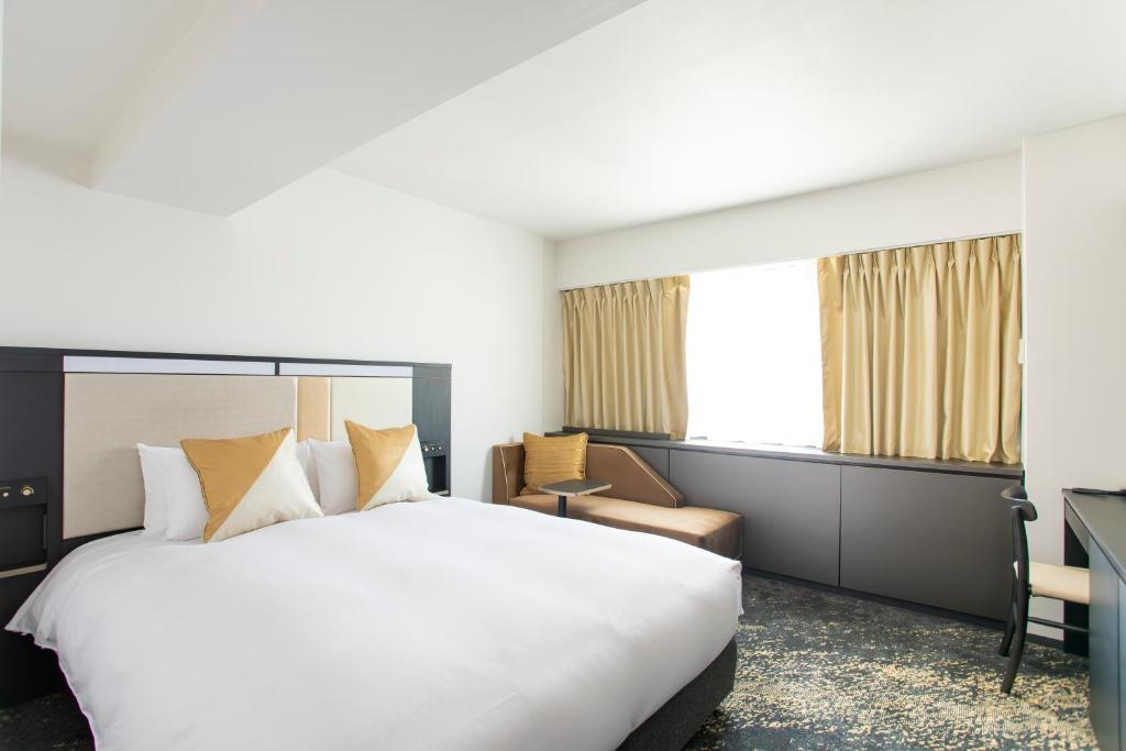 a hotel room with a large bed and a desk at Cross Hotel Osaka in Osaka