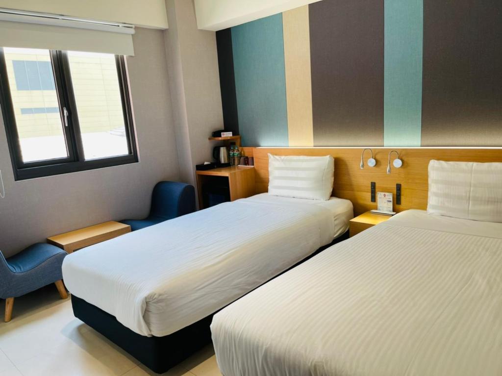 una camera d'albergo con due letti e una sedia di Fu Kuang Hotel a Città di Pingtung