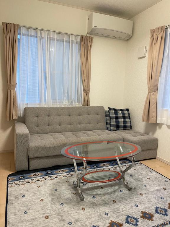 un soggiorno con divano e tavolo in vetro di Bessalov Home 2nd room friendly house a Tokyo