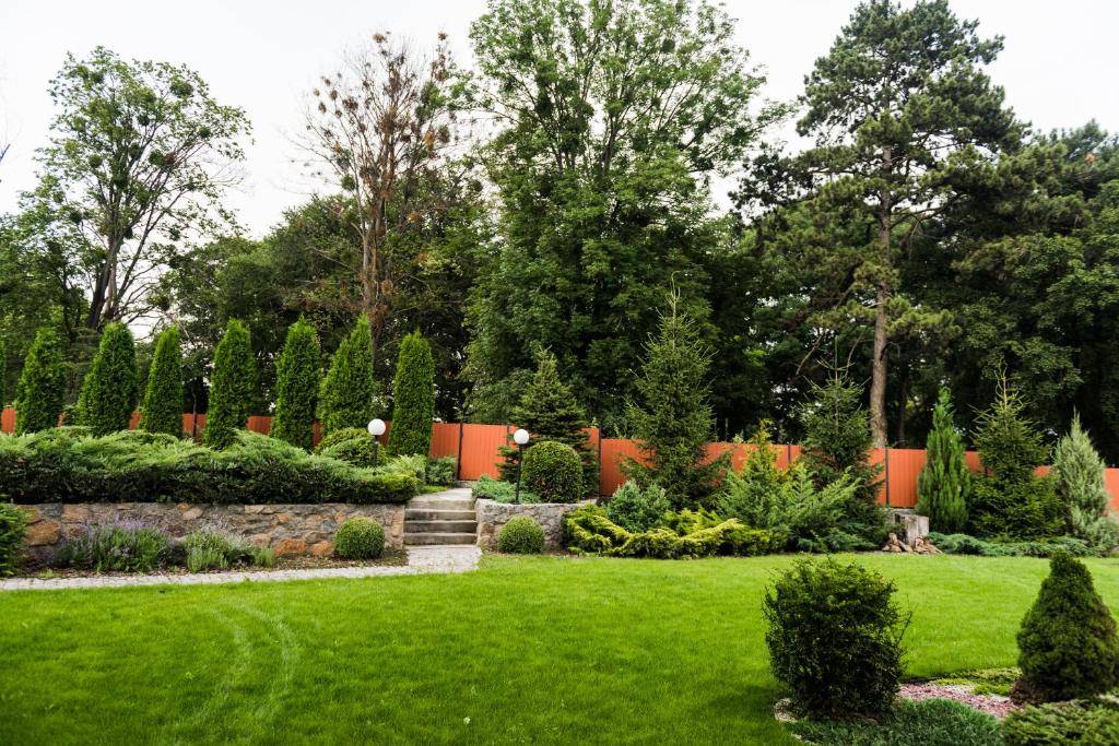un jardín con césped verde, arbustos y árboles en Golden park Apartments en Umanʼ