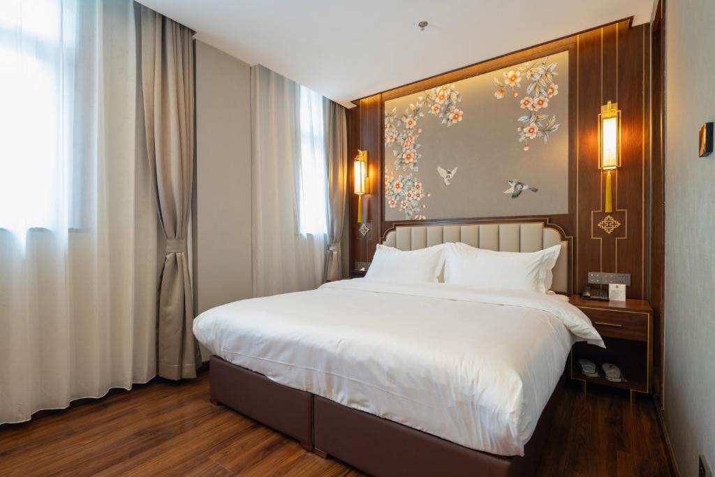 a bedroom with a large bed with white sheets at Pierr Palace Hotel (Beijing Nanluo Guxiang) in Beijing