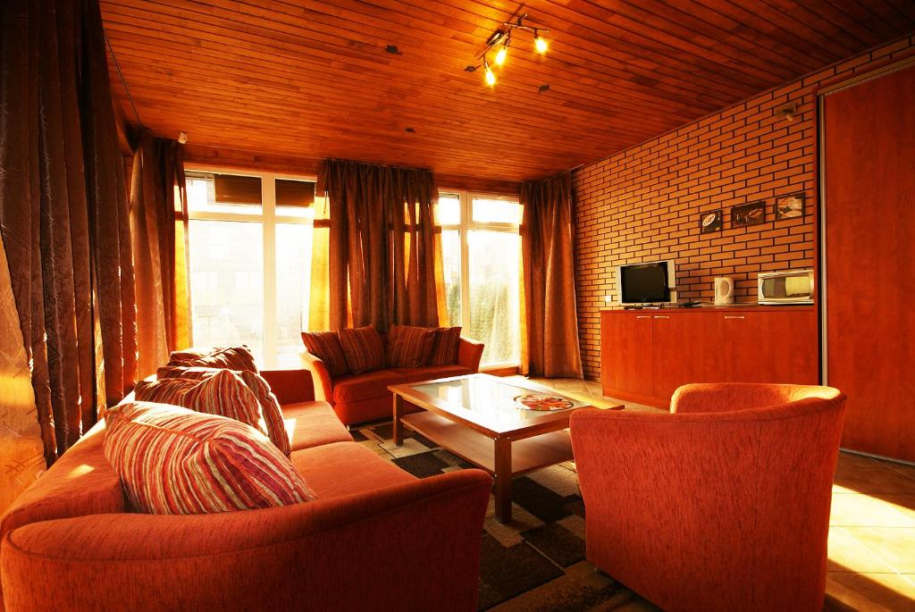 a living room with orange chairs and a coffee table at Vila Elena in Palanga