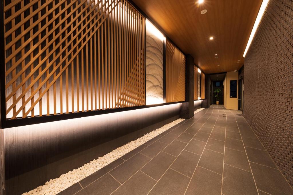 a hallway of a building with a wall and a tile floor at Shirakabanoyado - EBISU in Osaka