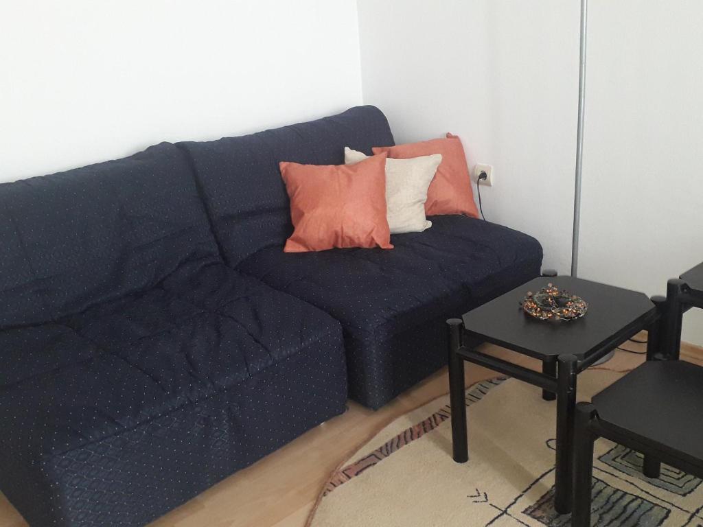 um sofá azul com almofadas e uma mesa num quarto em Kutak- stan na dan em Paraćin