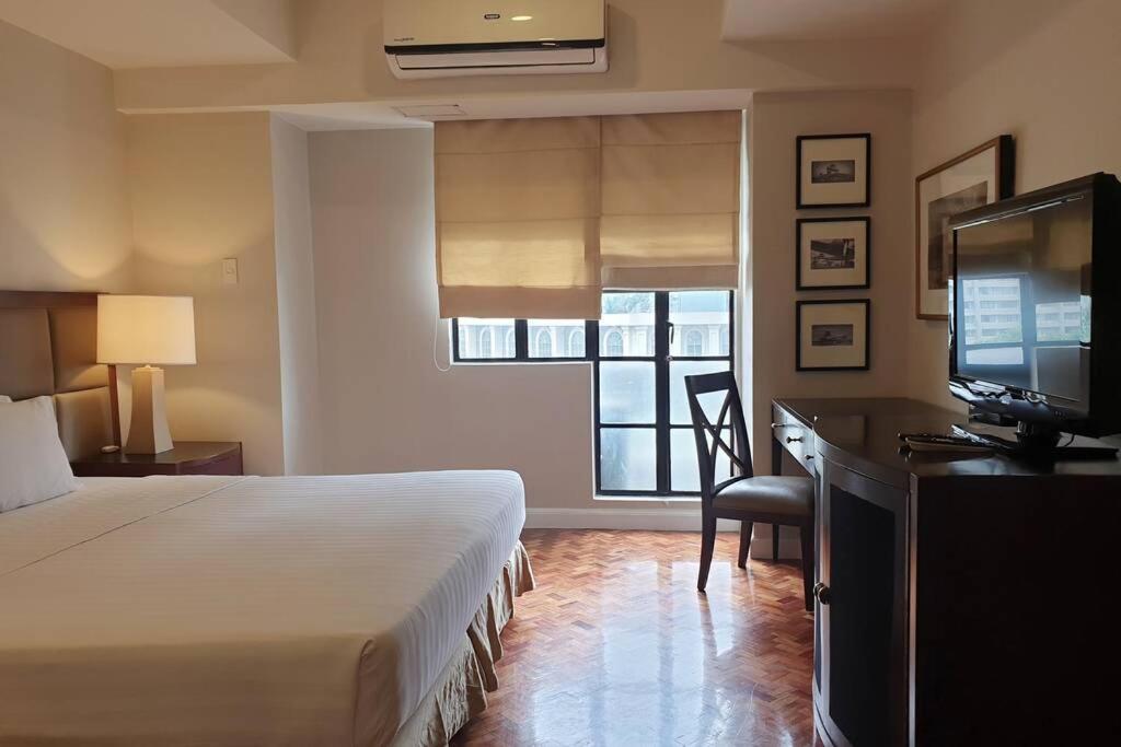 a hotel room with a bed and a desk and a television at Studio at Olympia Makati GREAT Location, Vaccination Card Required in Manila