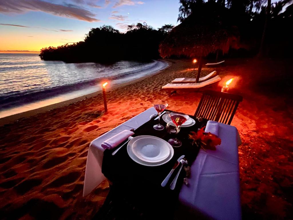 una mesa en la playa con un plato de comida en Hotel Océan Beach Sakatia en Nosy Be