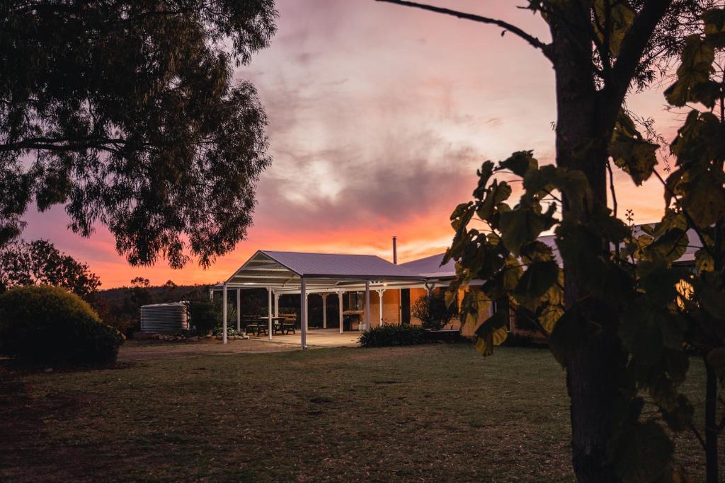 a house with a sunset in the background at Glen Mervyn Lodge in Mummballup