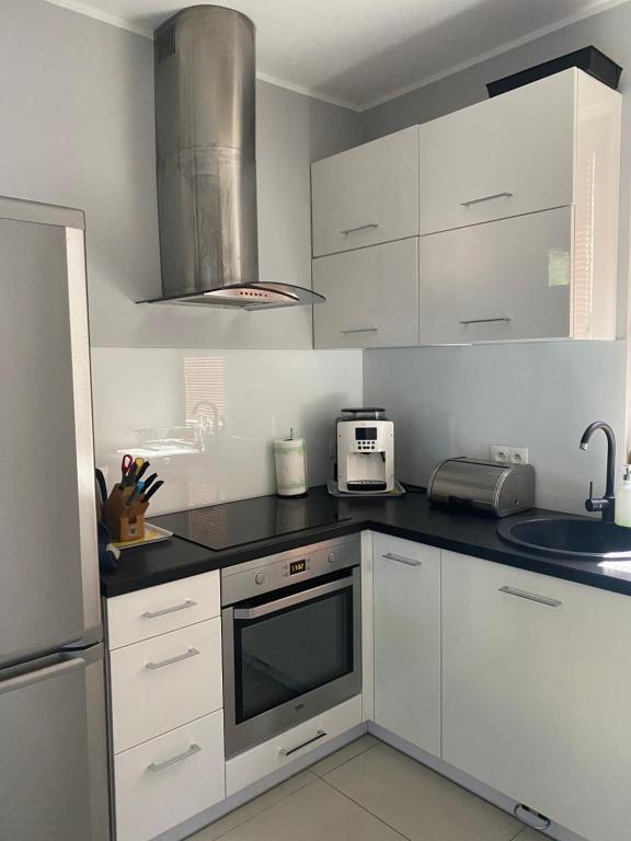 kuchnia z białymi szafkami i mikrofalówką w obiekcie Hire House w Pobierowie