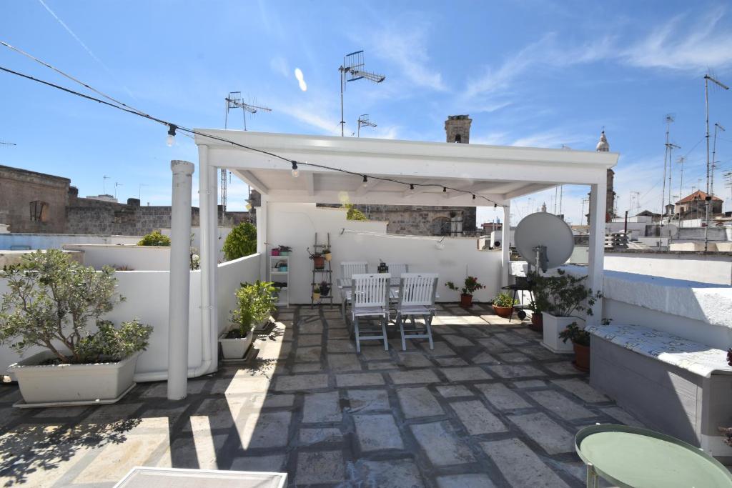 eine weiße Terrasse mit Stühlen und Tischen auf dem Dach in der Unterkunft Casa RoSiLù in Monopoli