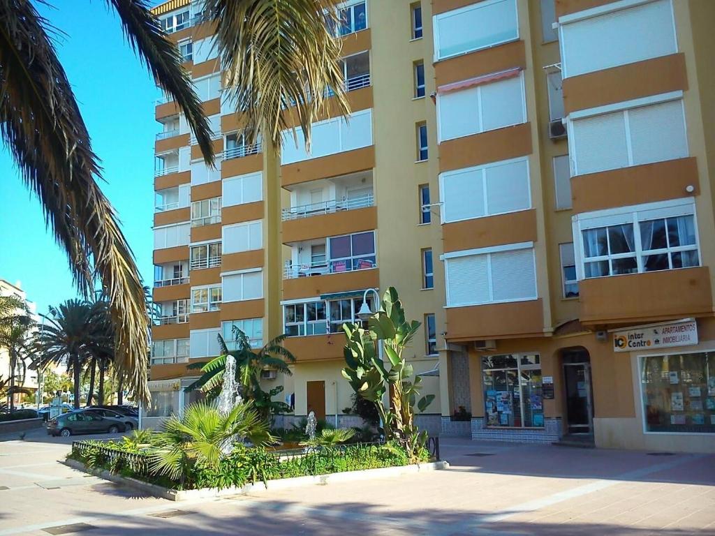 wysoki żółty budynek z palmami przed nim w obiekcie Estudio sol y playa w mieście Algarrobo-Costa