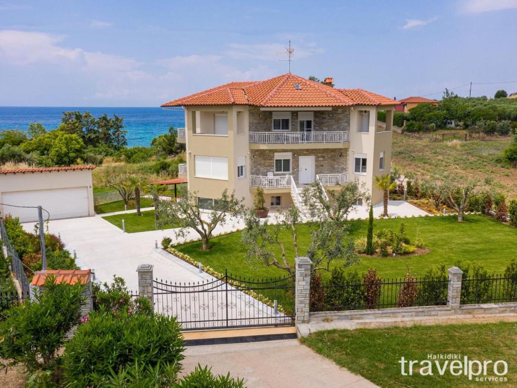 a house with a gate in front of the ocean at Villa Zeria by RentalsPro - Nea Potidaia Halkidiki in Nea Potidaea