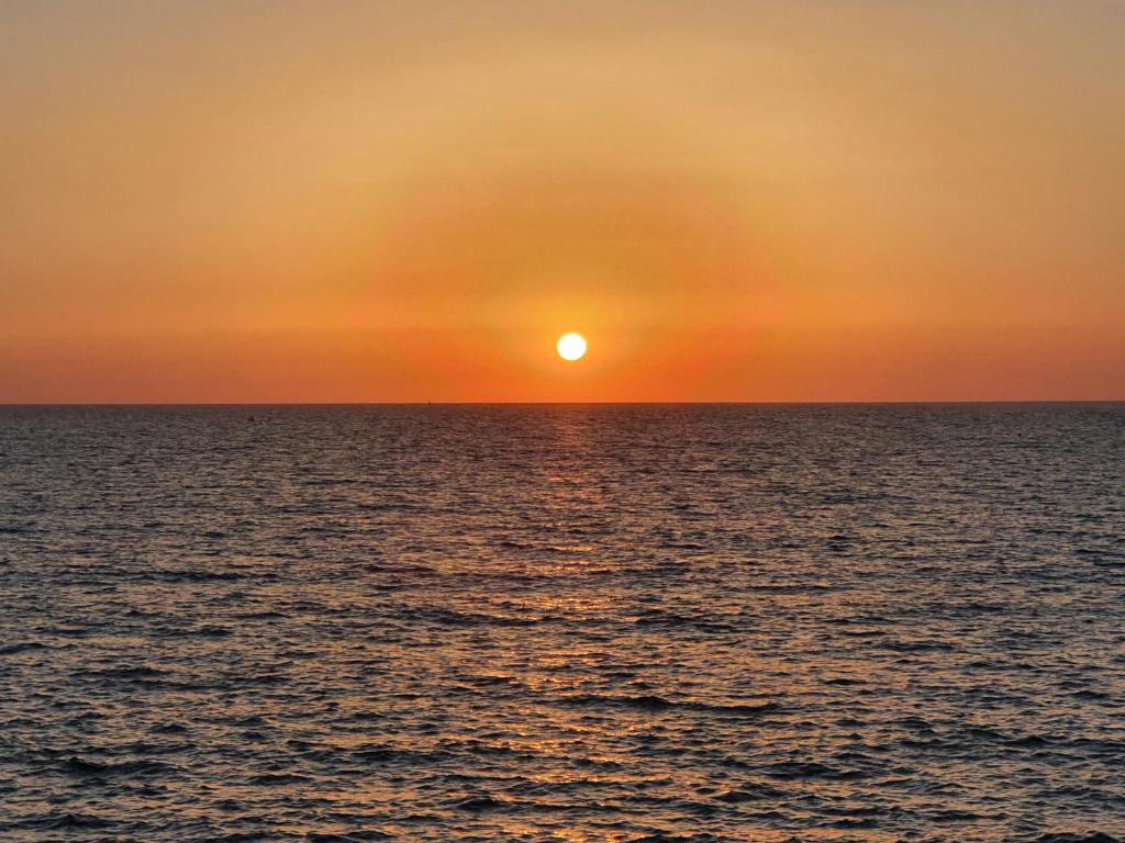 een zonsondergang boven de oceaan met zonsondergang bij Torre de Arena y Playa in Sanlúcar de Barrameda