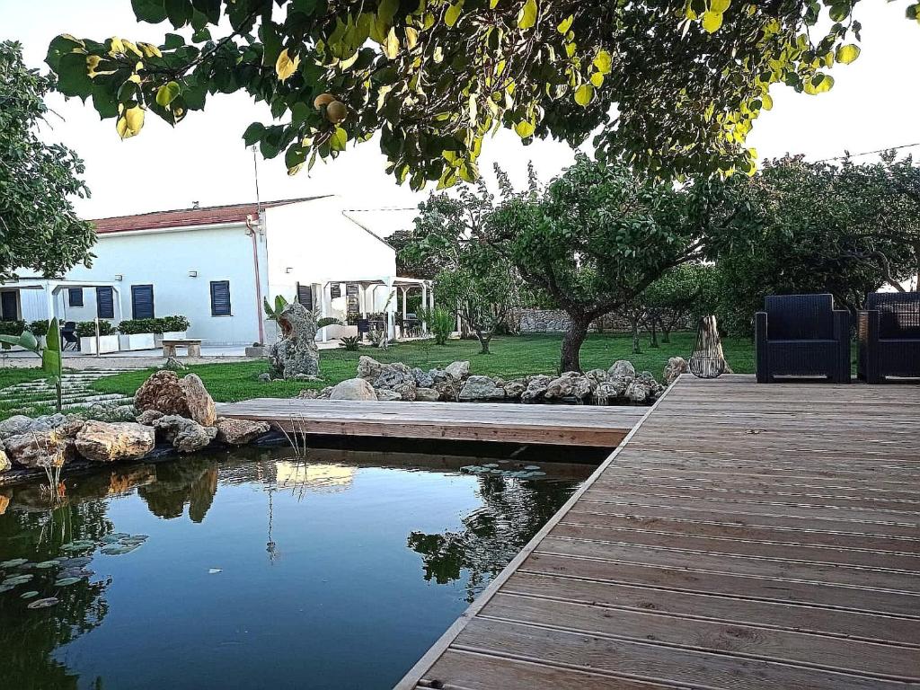 einen Holzsteg, der zu einem Teich im Hof führt in der Unterkunft Giardino D'Oriente in Otranto