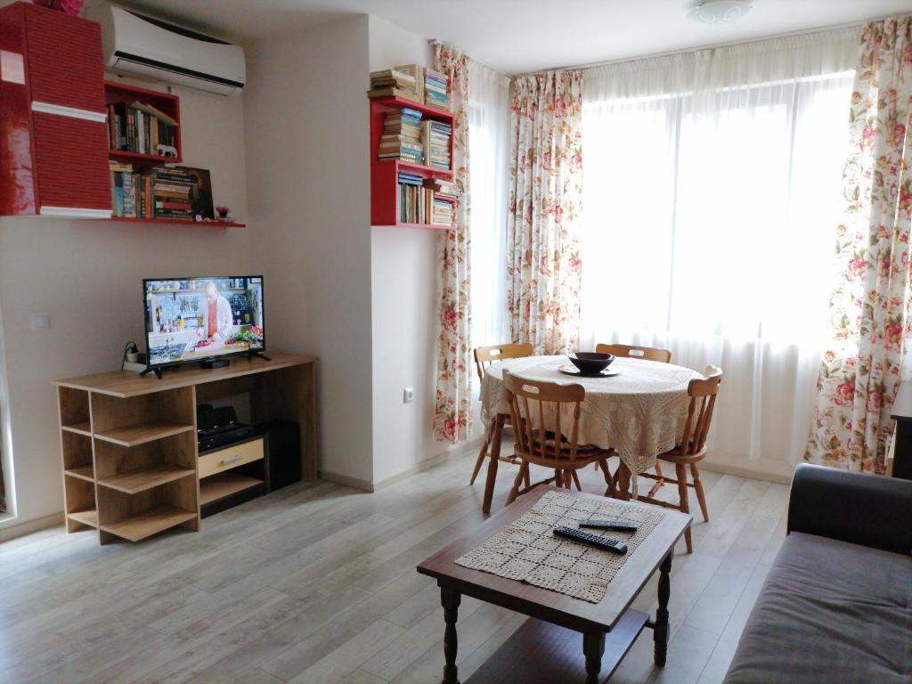 a living room with a table and a tv at White home-apartament in Burgas