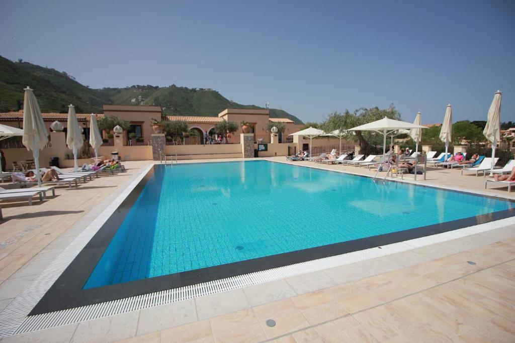 チェファルにあるSun House con piscina by Wonderful Italyの- リゾート内のスイミングプール(椅子に座る人々付)