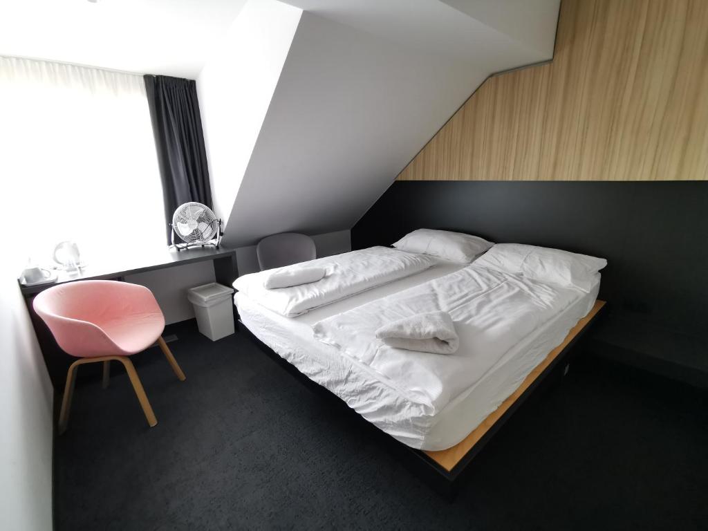 a bedroom with a bed and a chair and a window at Cha Cha Rooms in Ljubljana