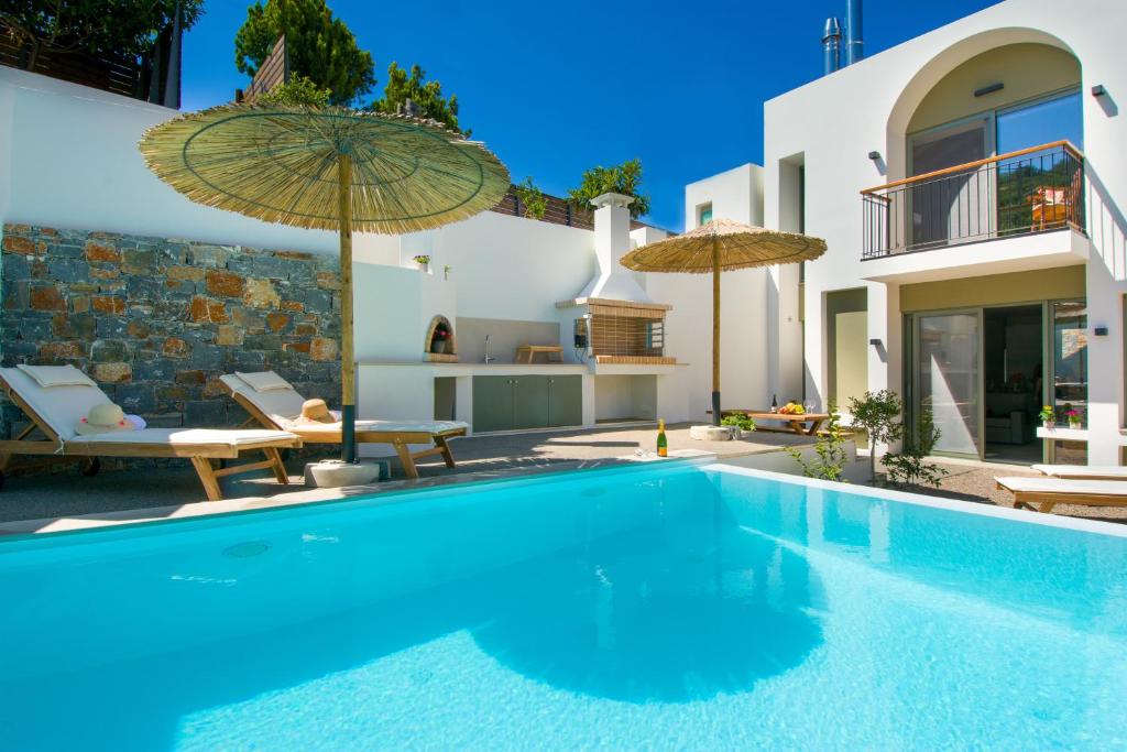 uma piscina com guarda-sóis ao lado de uma casa em Pakio Luxury Villa : Private Cretan Holidays em Milatos
