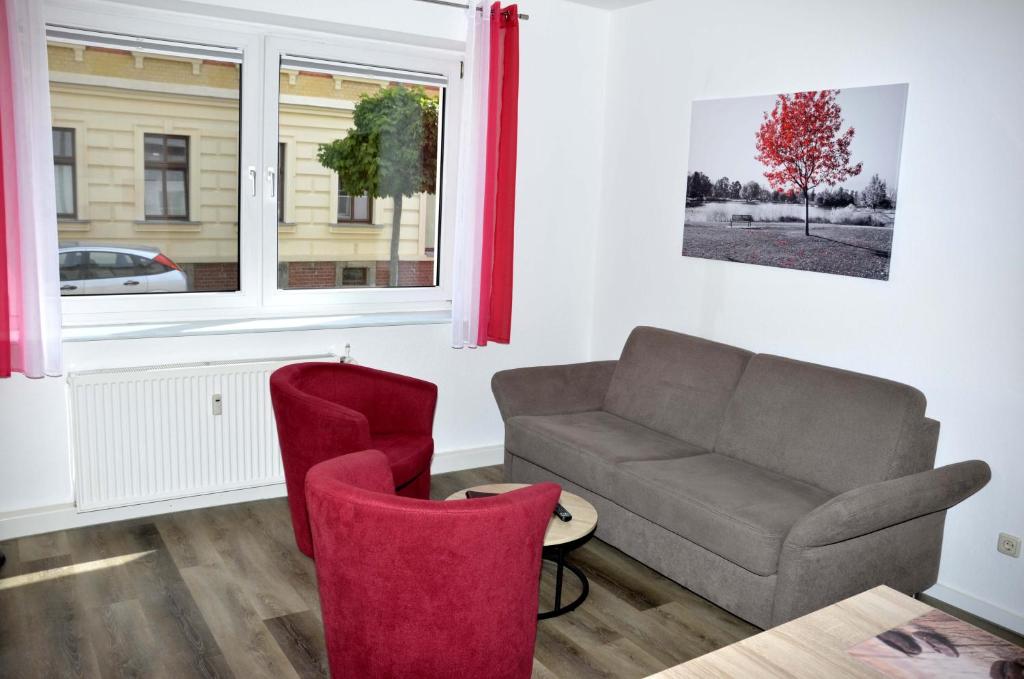 a living room with a couch and red chairs at Ferienwohnung am Wasserturm in Zwenkau