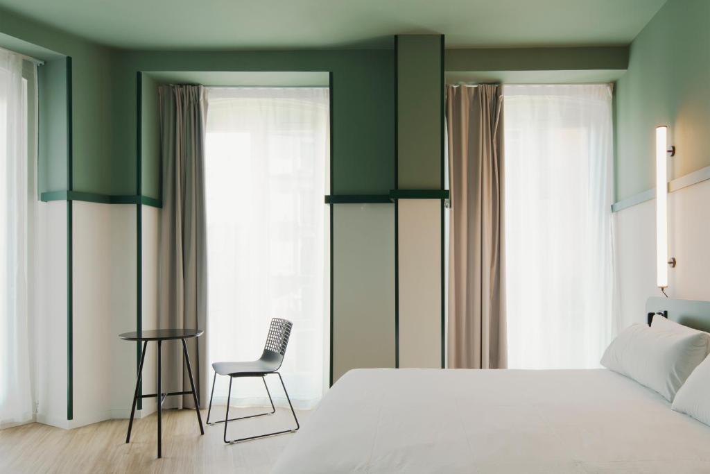 a bedroom with a white bed and a chair at B&B HOTEL Madrid Centro Plaza Mayor in Madrid