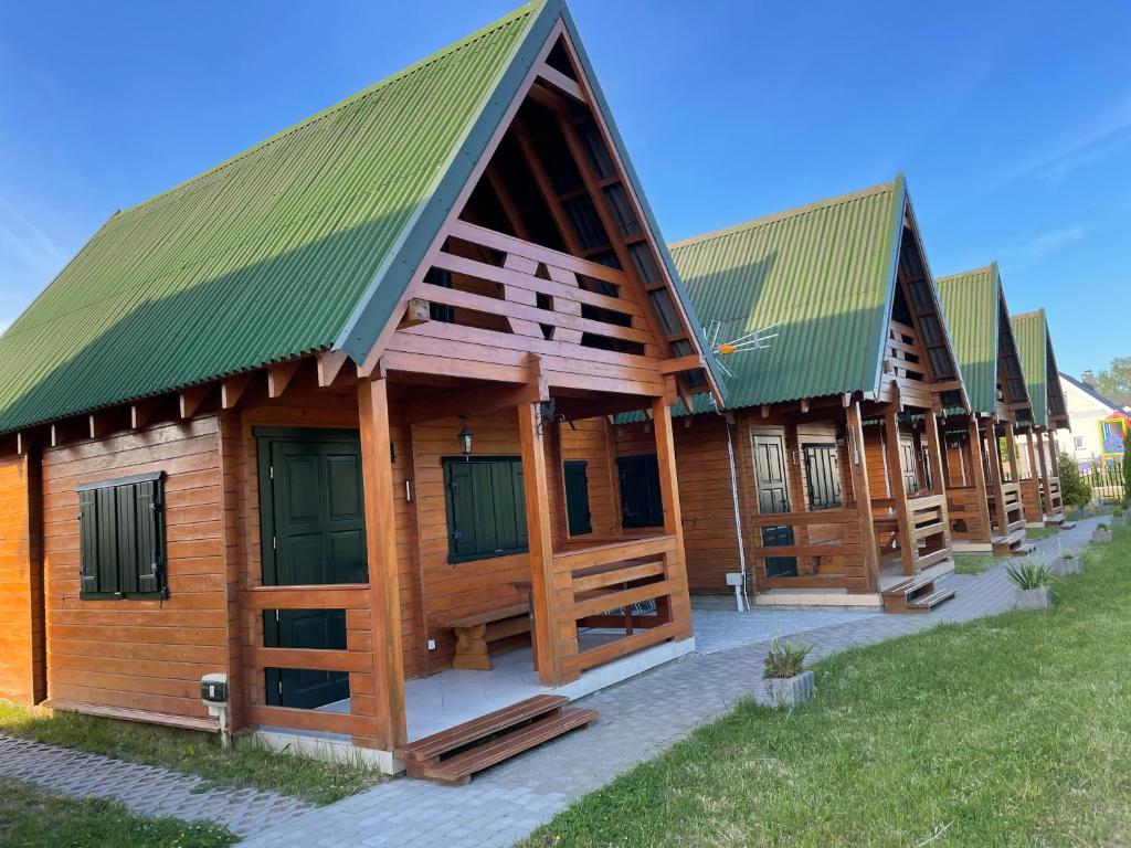 wiersz drewnianych budynków z zielonymi dachami w obiekcie Domki Letniskowe Malinka w mieście Bobolin