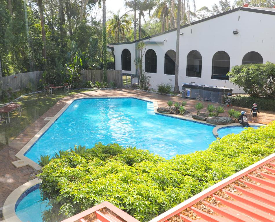 uma grande piscina azul ao lado de um edifício branco em Checkers Resort em Terrey Hills