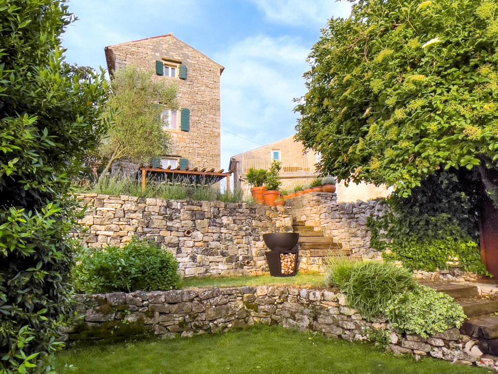 a garden with a stone wall and a building at Holiday Home Bale - Valle in Bale