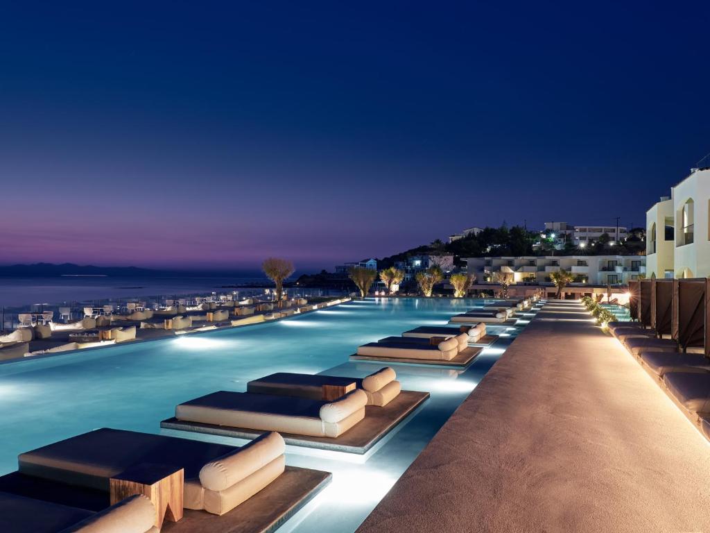 a hotel swimming pool with lounge chairs at night at Caravel Suites - Adults Only in Tsilivi